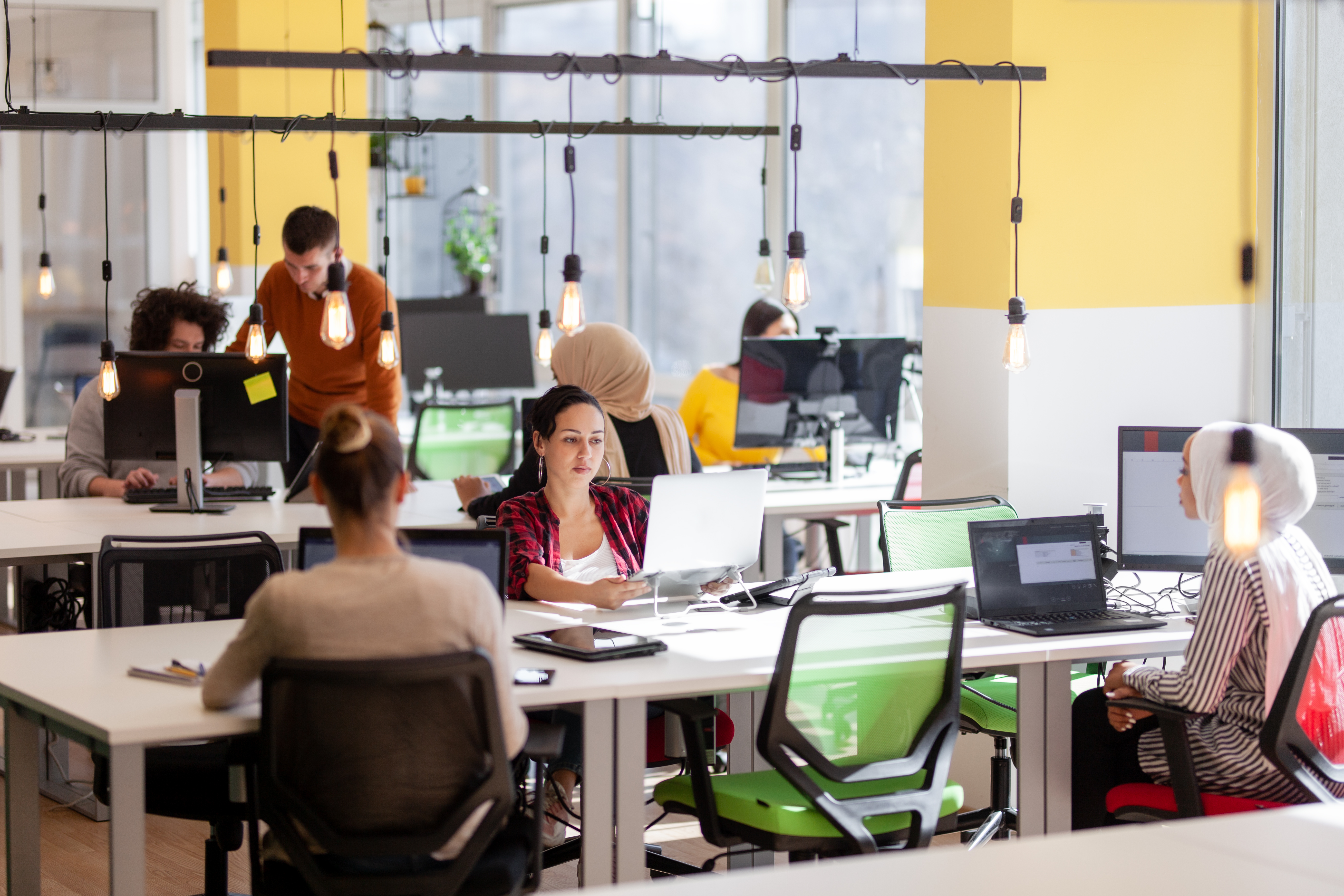 Creative Team Of Young Individuals Working On Desktop Computers In A Modern Office Space